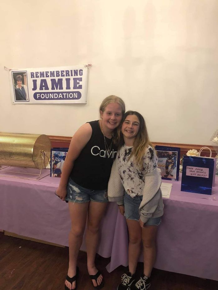 two girls standing next to each other in front of a sign that says jamie foundation
