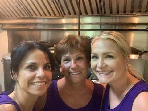 three women are posing for a picture in a kitchen .