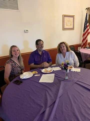 a group of people are sitting at a table with plates of food .