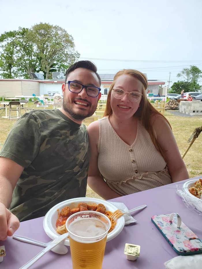 a man and a woman are sitting at a table eating pizza and drinking beer .