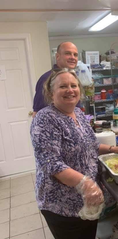 a man and a woman are standing in a kitchen preparing food .