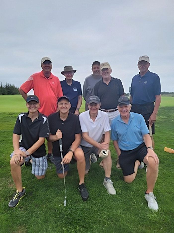 a group of men are posing for a picture on a golf course .