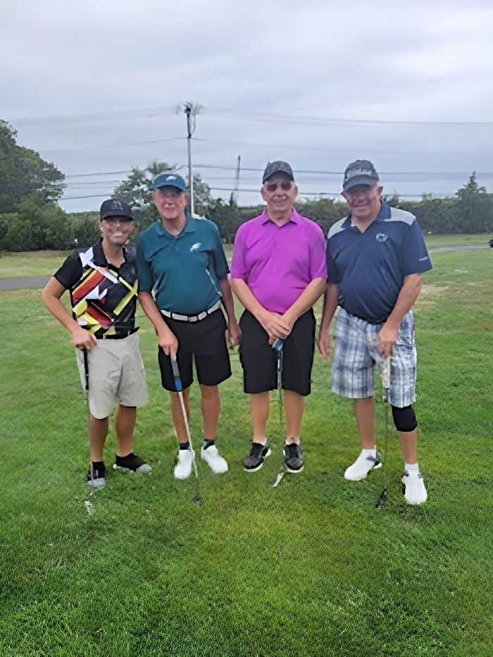 a group of men are posing for a picture on a golf course .