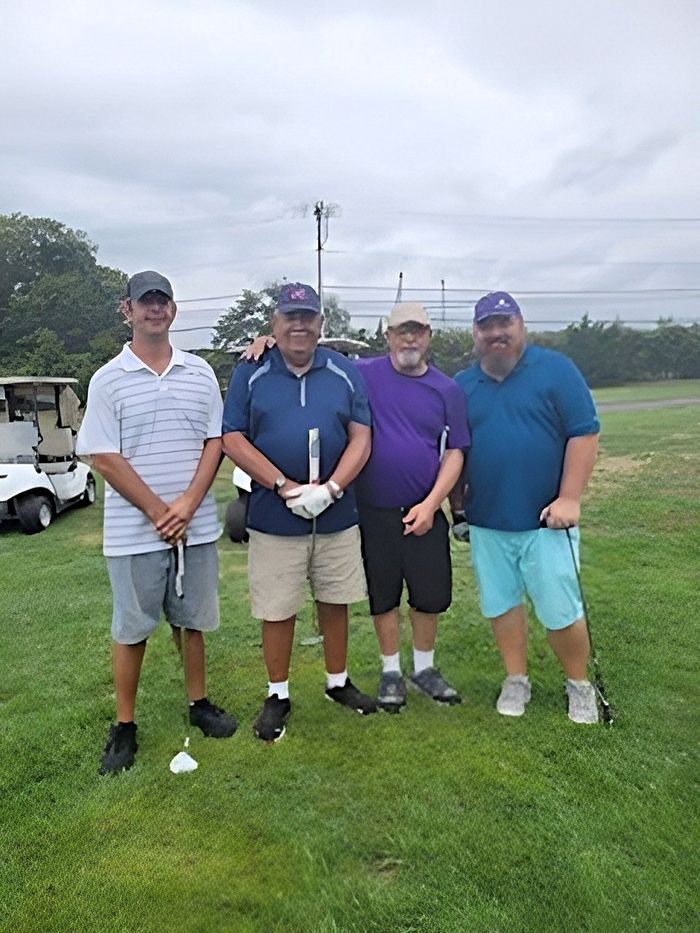 a group of men are posing for a picture on a golf course .