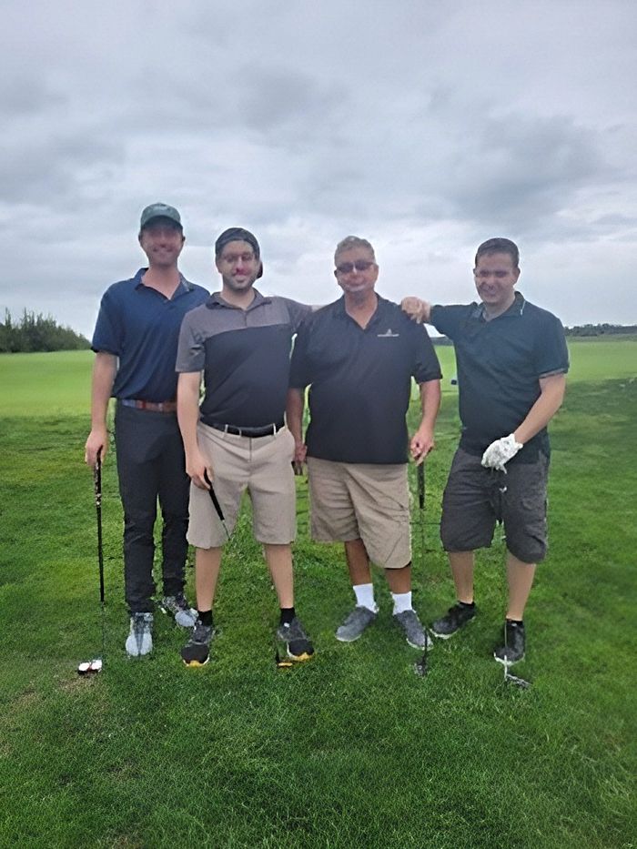 a group of men are posing for a picture on a golf course .