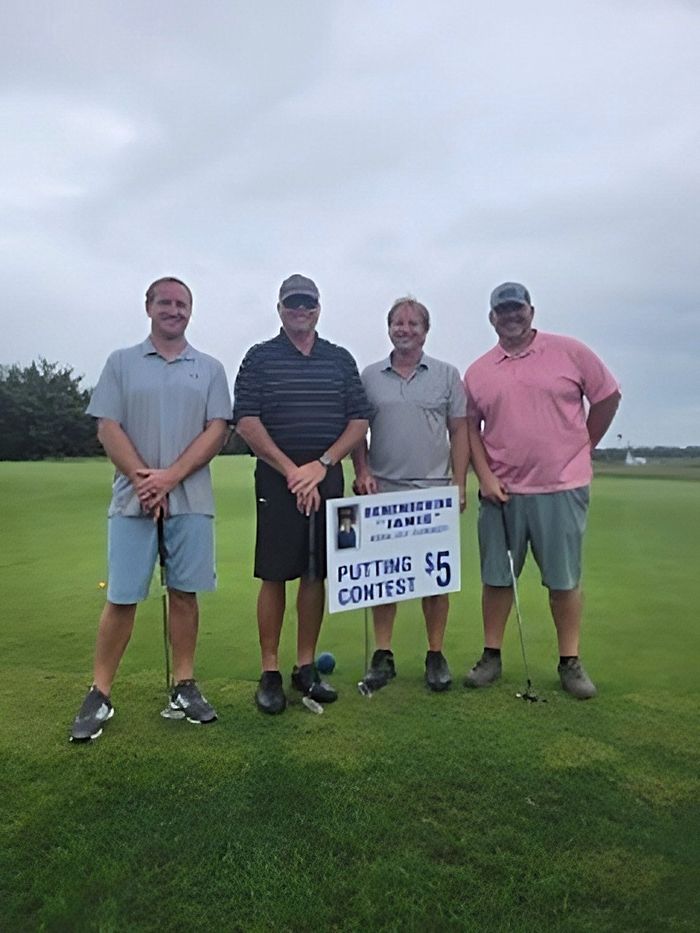 a group of men are standing on a golf course holding golf clubs .