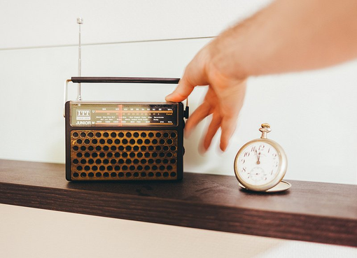re to check out our media page to hear them. a hand is reaching for a radio next to a pocket watch