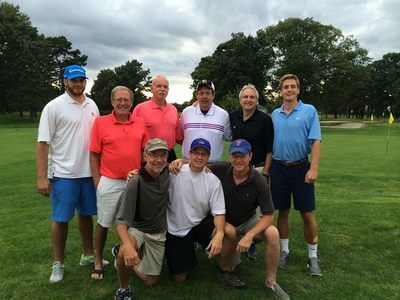 a group of men are posing for a picture on a golf course .