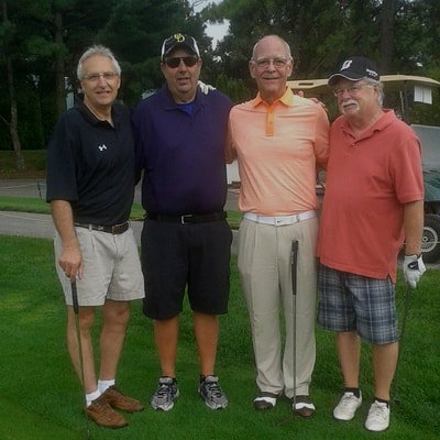 a group of men are posing for a picture on a golf course .