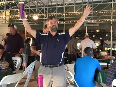 a man is holding a trophy over his head in a crowded room .