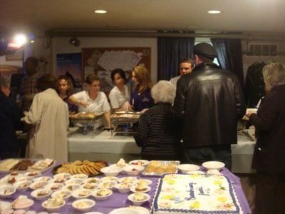 a group of people are gathered around a table with a cake that says jesus on it