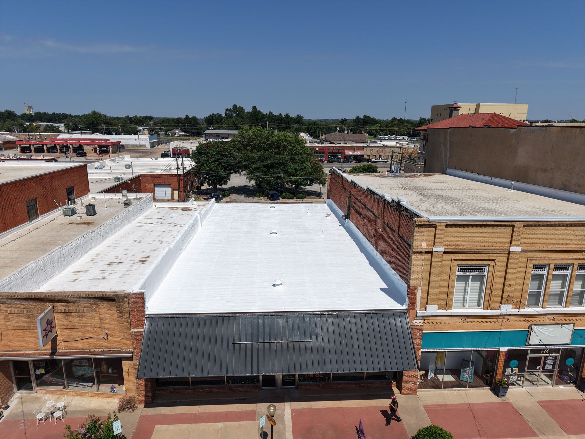 Aerial view of downtown buildings with white and brick rooftops under a clear sky.