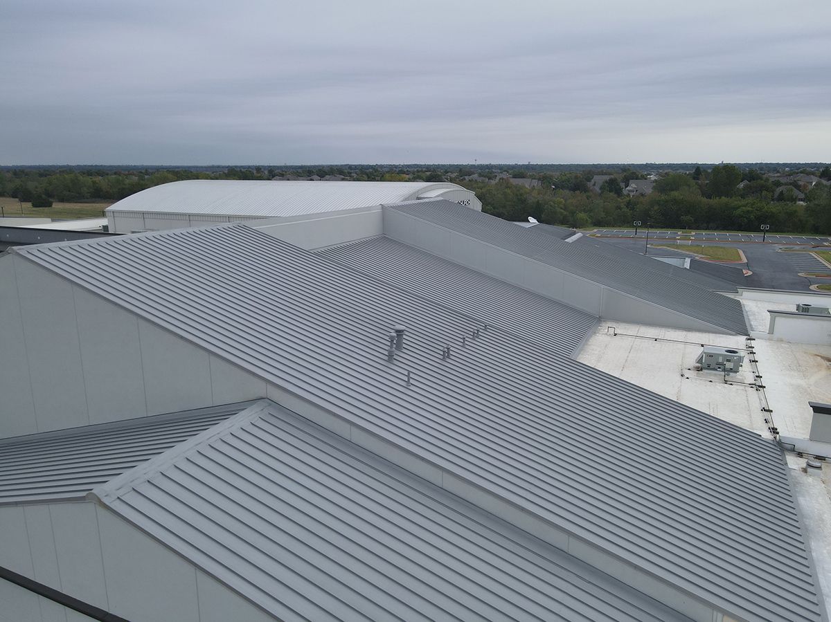 Aerial view of a modern building with a corrugated metal roof on a cloudy day.