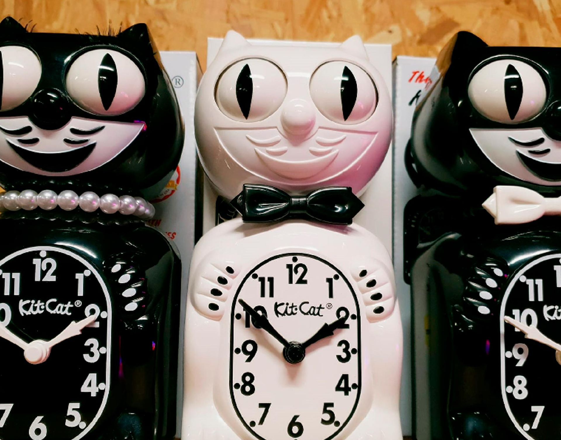 Trois horloges Kit-Cat Klock en forme de chat : deux noires à cadran blanc et une blanche.
