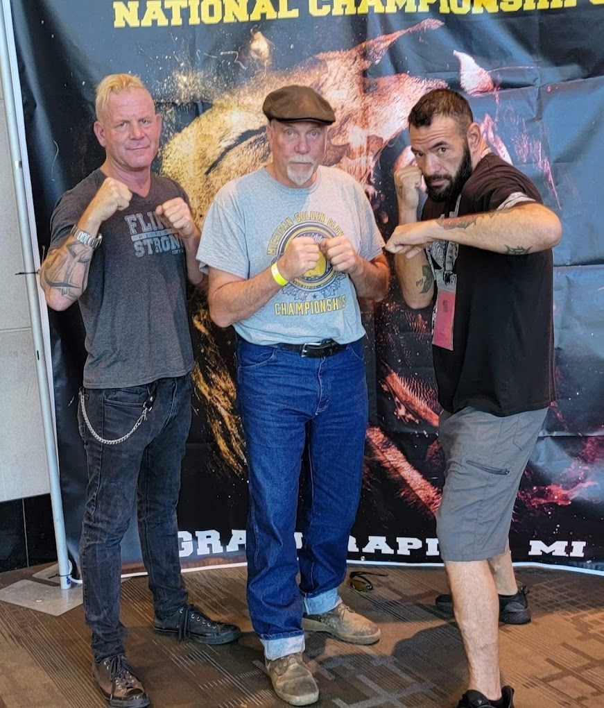Three men are posing for a picture in front of a national champions banner.