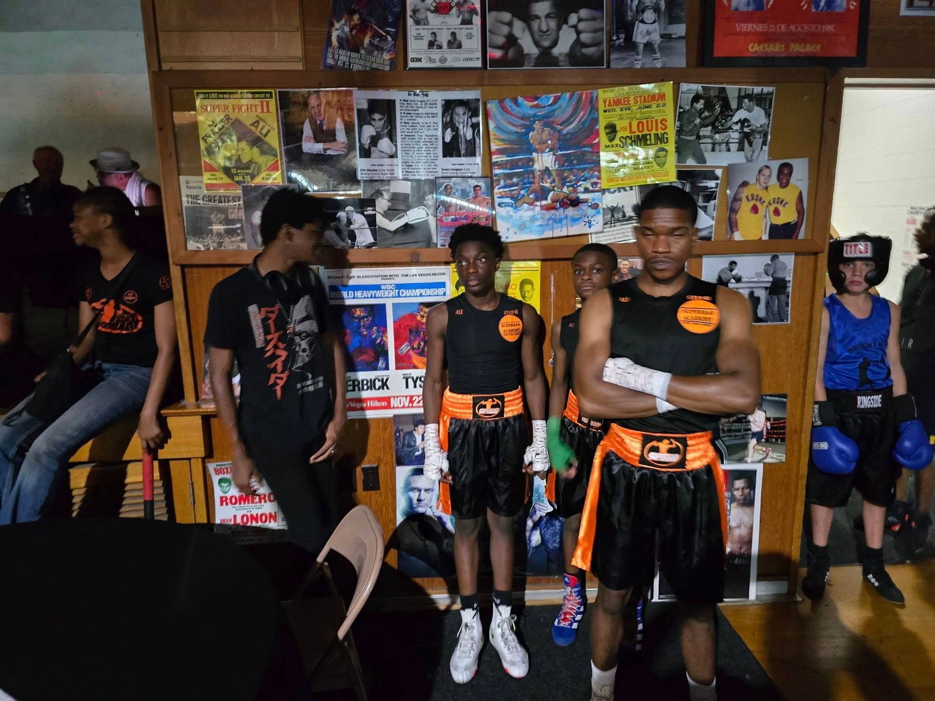 A group of young men are standing in front of a wall with boxing posters on it