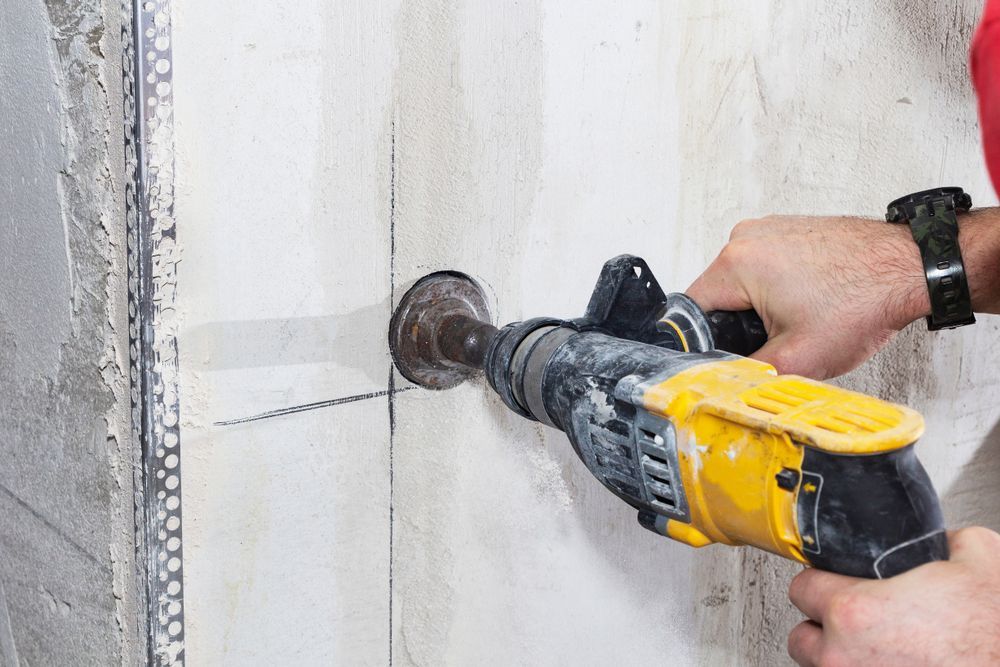Person Drills a Hole in a Light-colored Wall — Coastcut Concrete Cutting Pty Ltd in Port Stephens, NSW