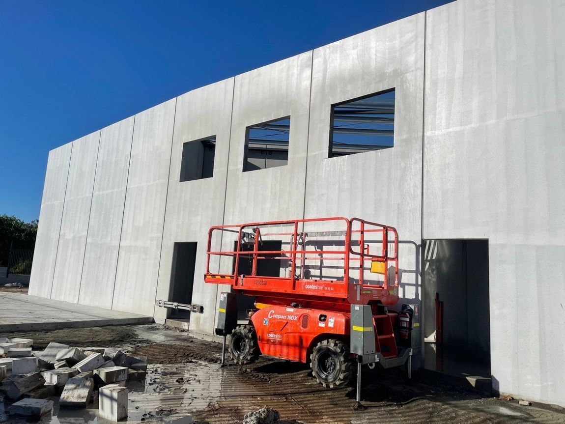 Orange Lift in Front of a Concrete Building Under Construction — Coastcut Concrete Cutting Pty Ltd in Corlette, NSW