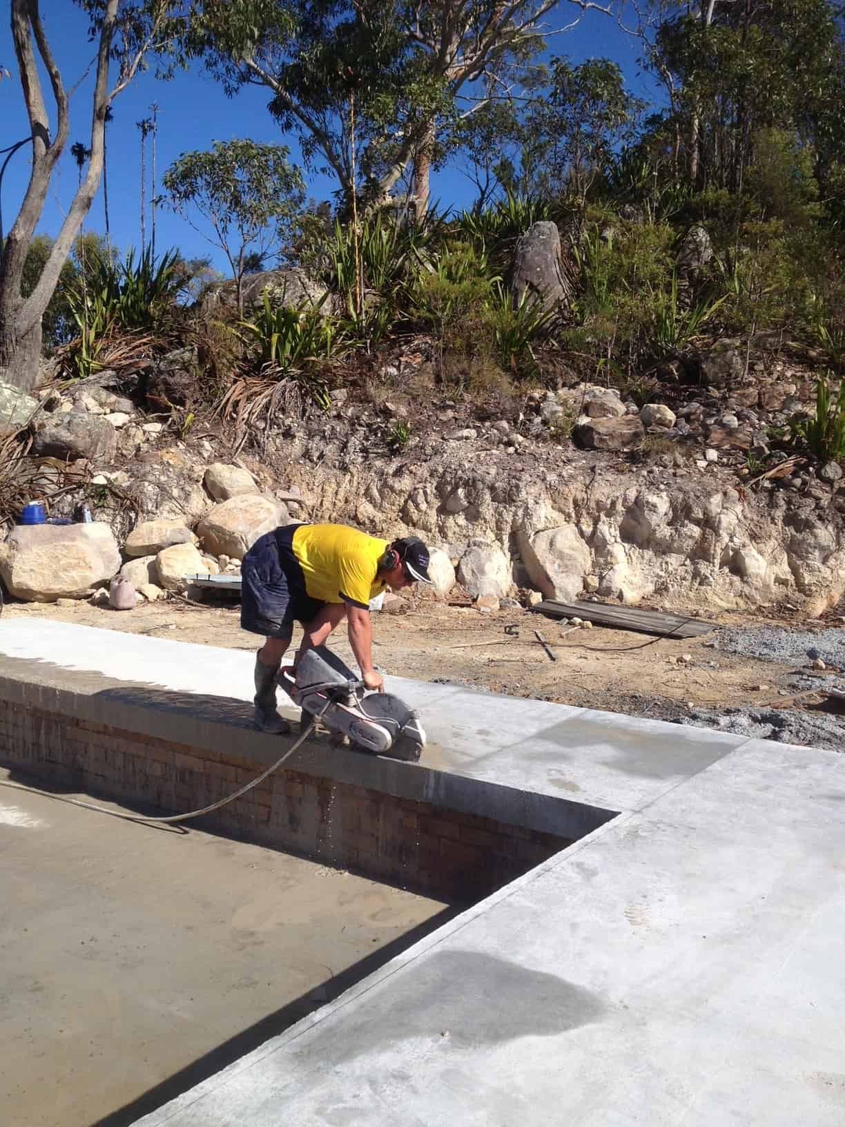 Person in Yellow Shirt Cutting Concrete With a Power Saw Outdoors — Coastcut Concrete Cutting Pty Ltd in Corlette, NSW