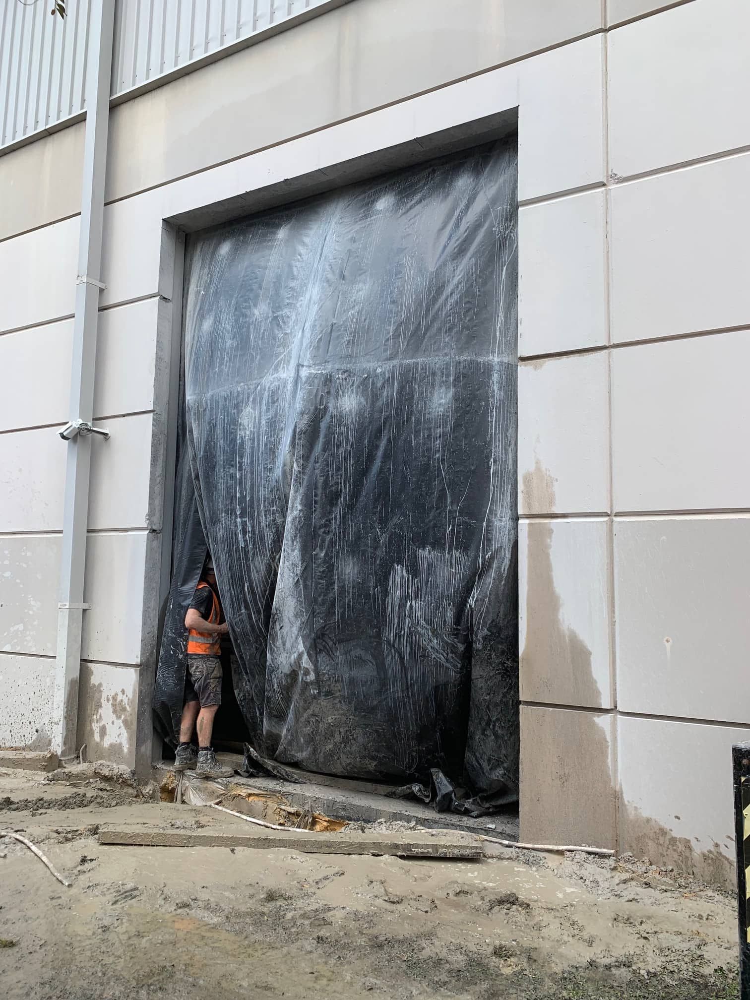 Man Standing in Front of a Black Tarp Covering a Large Doorway — Coastcut Concrete Cutting Pty Ltd in Port Stephens, NSW