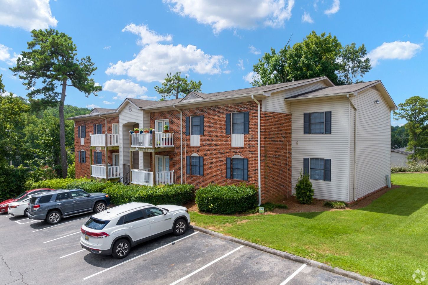 A brick apartment building with cars parked in front of it.