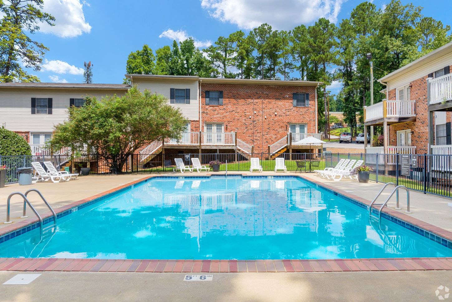 There is a large swimming pool in front of a brick building.