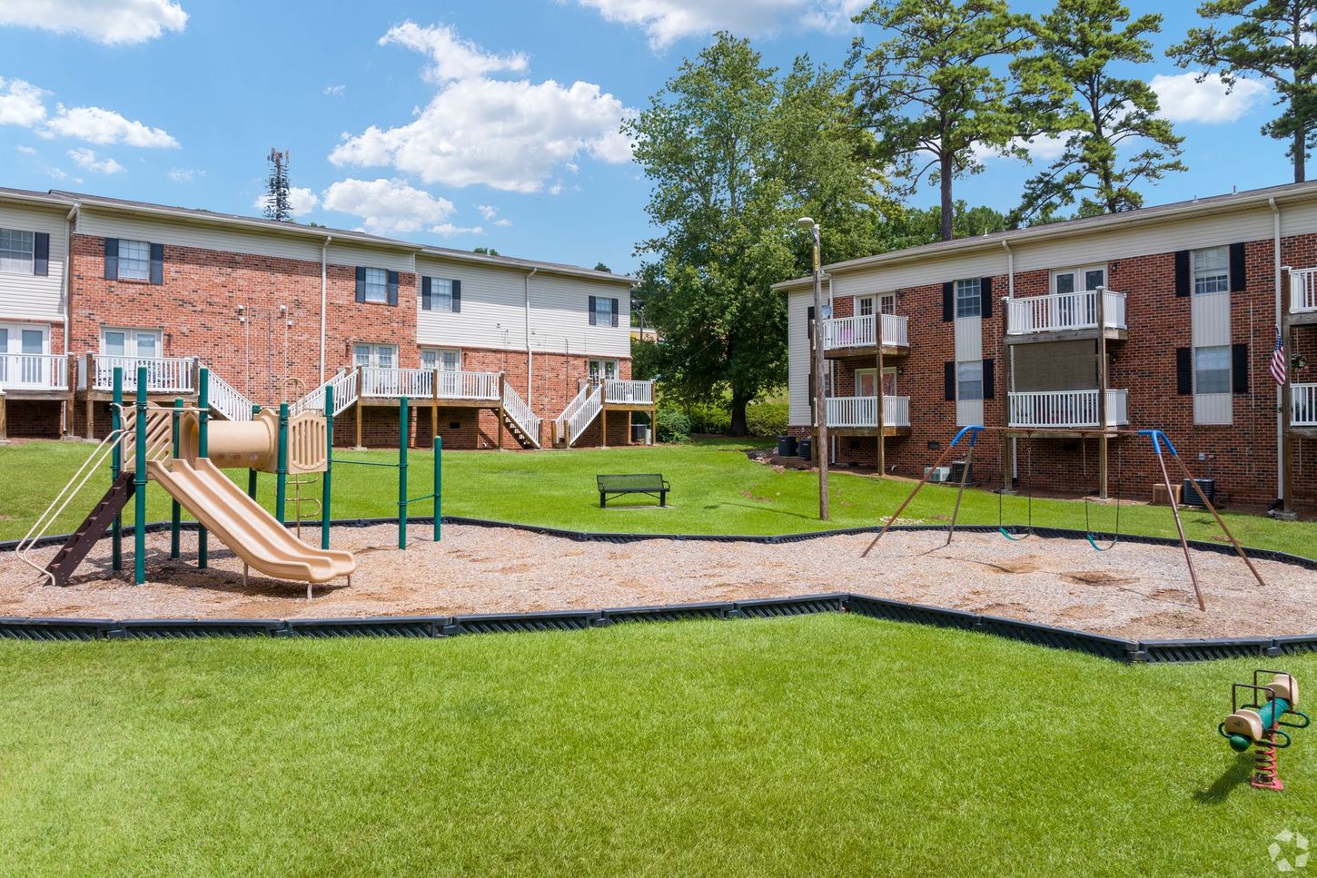 A playground in front of a brick building with a slide and swings.