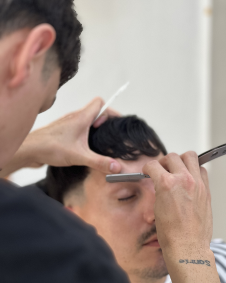 Un barbero perfila las cejas de su cliente