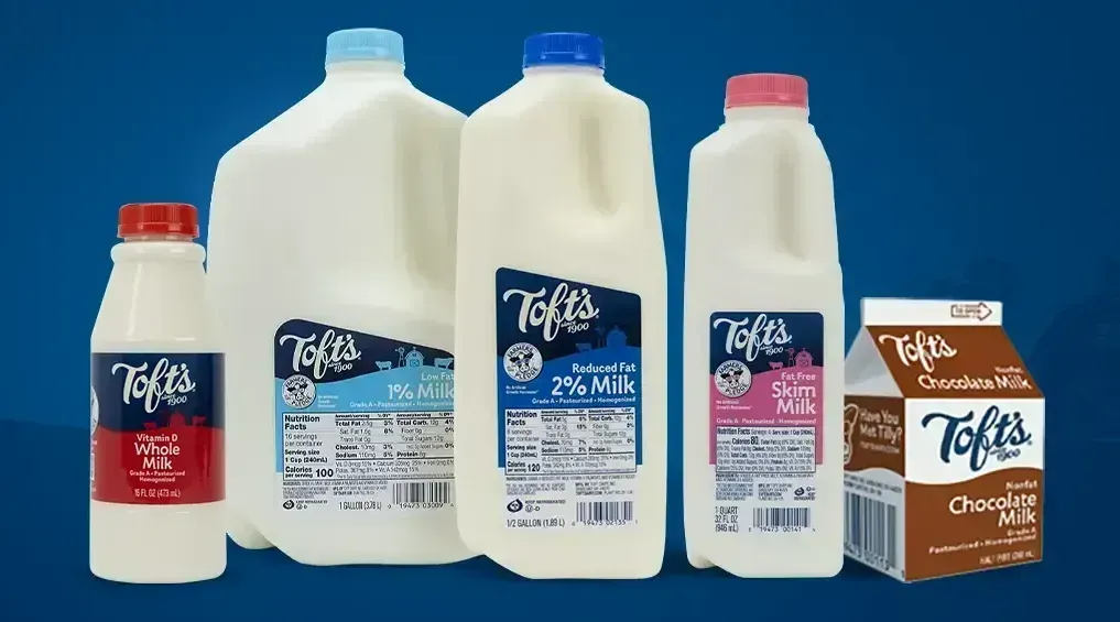 Several bottles of Toft's milk are lined up on a blue background