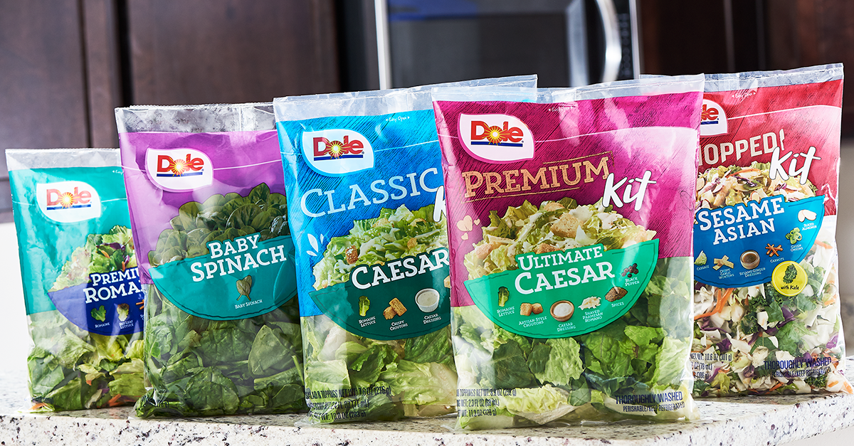 A group of Dole Salad bags sitting on top of a counter.