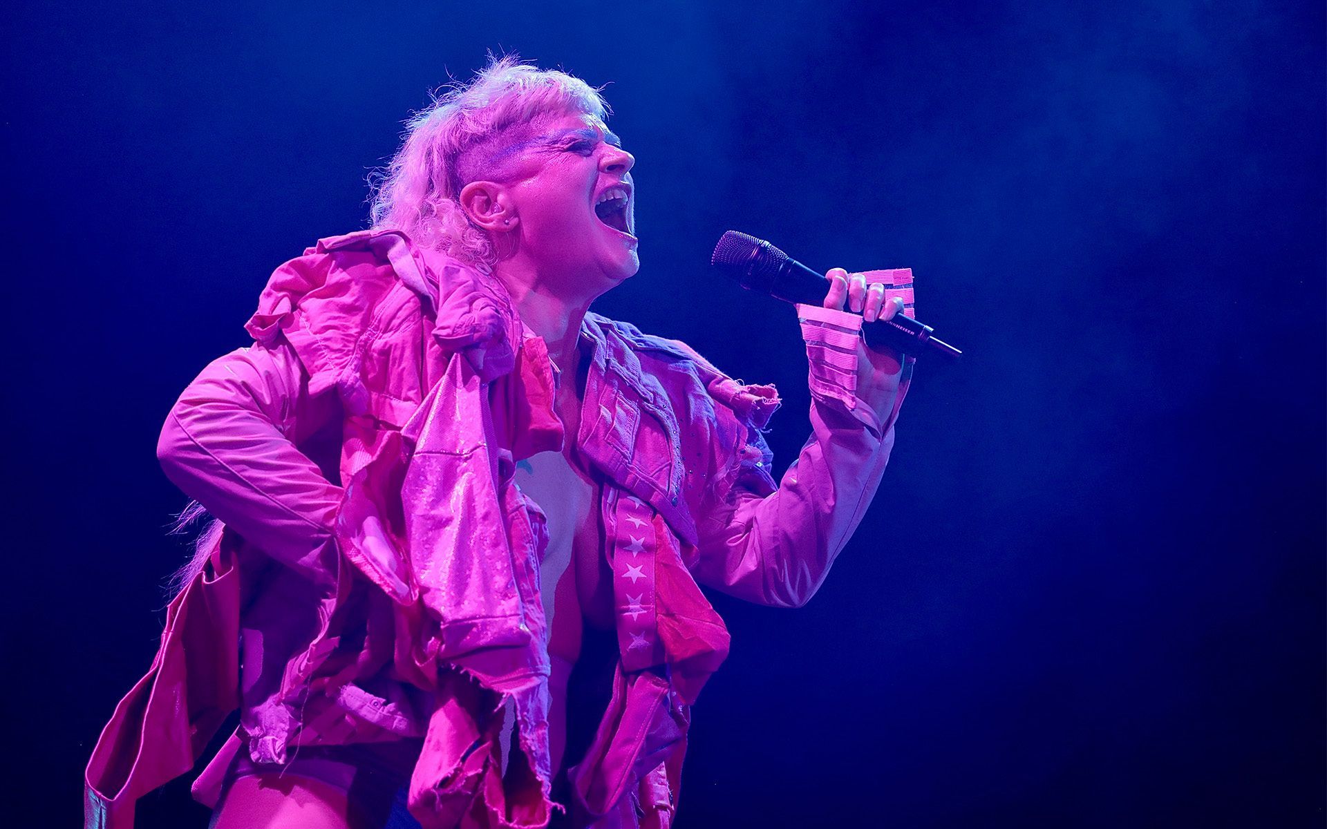 Eine Frau in einer rosa Jacke, die in ein Mikrofon singt