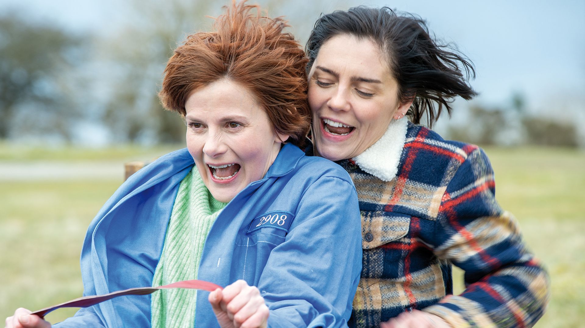 Zwei Frauen lachen und eine trägt eine blaue Jacke