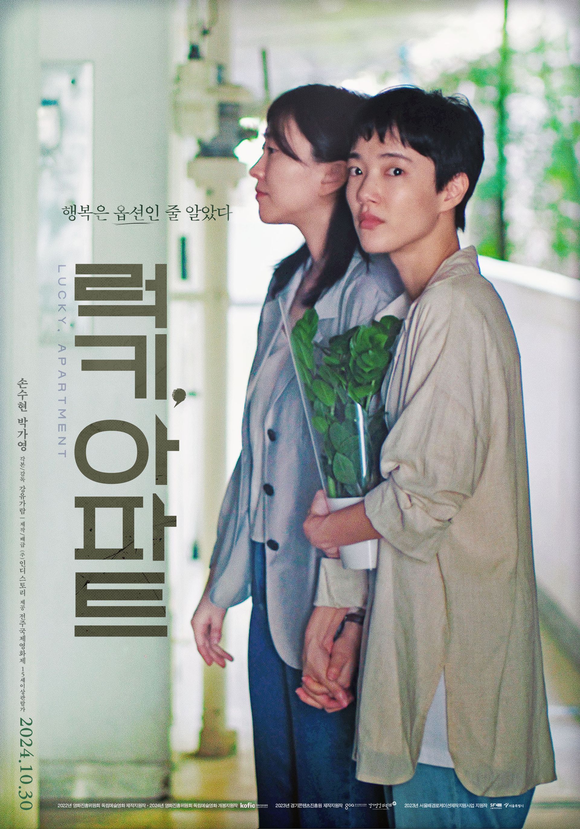 Zwei Frauen, eine mit Pflanzen in der Hand, stehen in einem Flur. Eine blickt in die Kamera. Poster zum Film