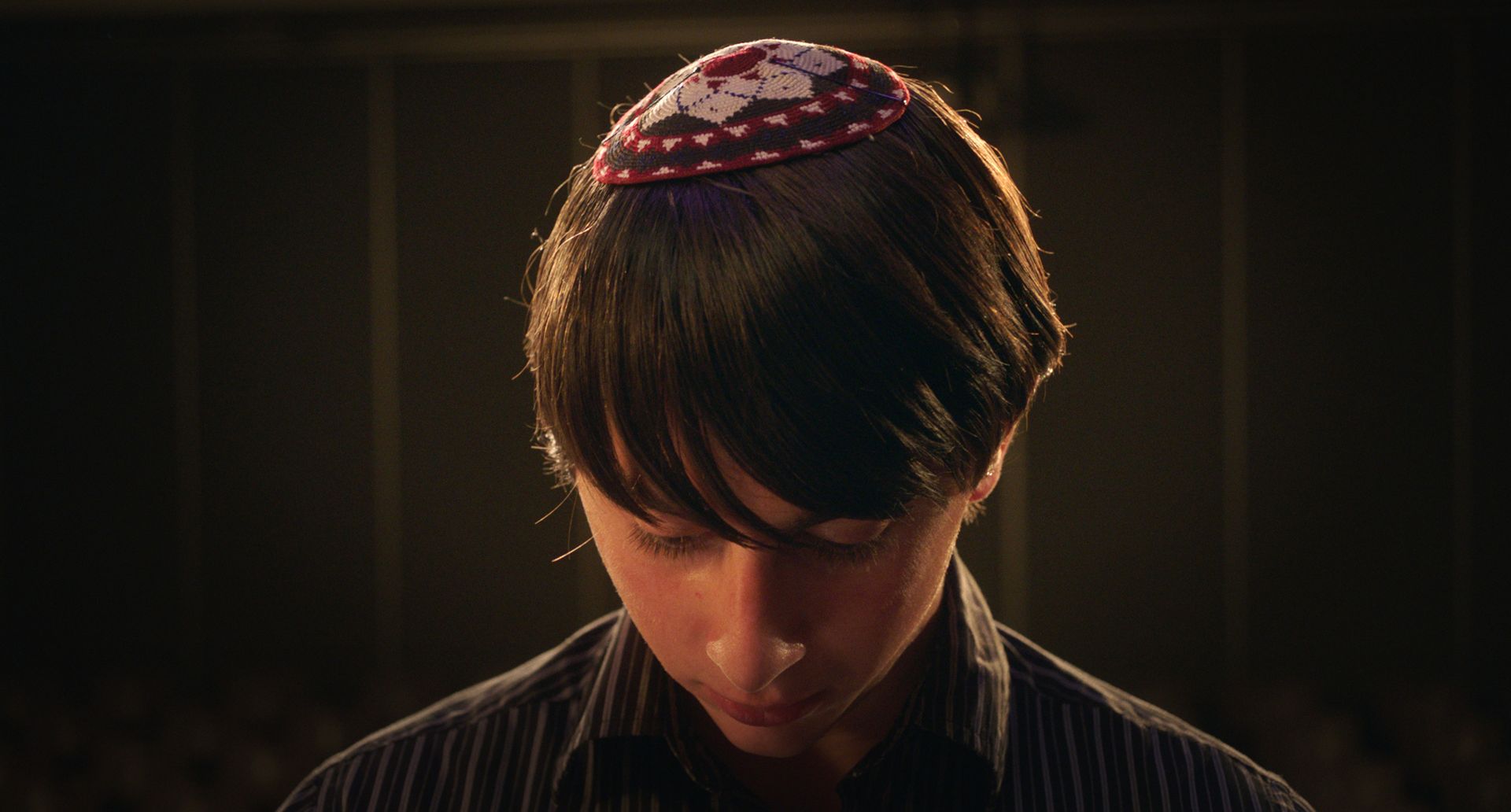 Ein kleiner Junge mit einer Kippa auf dem Kopf schaut nach unten