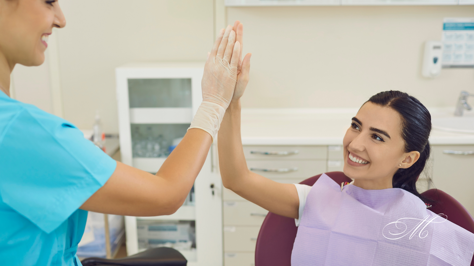 A dentist and a patient are giving each other a high five in a dental office.