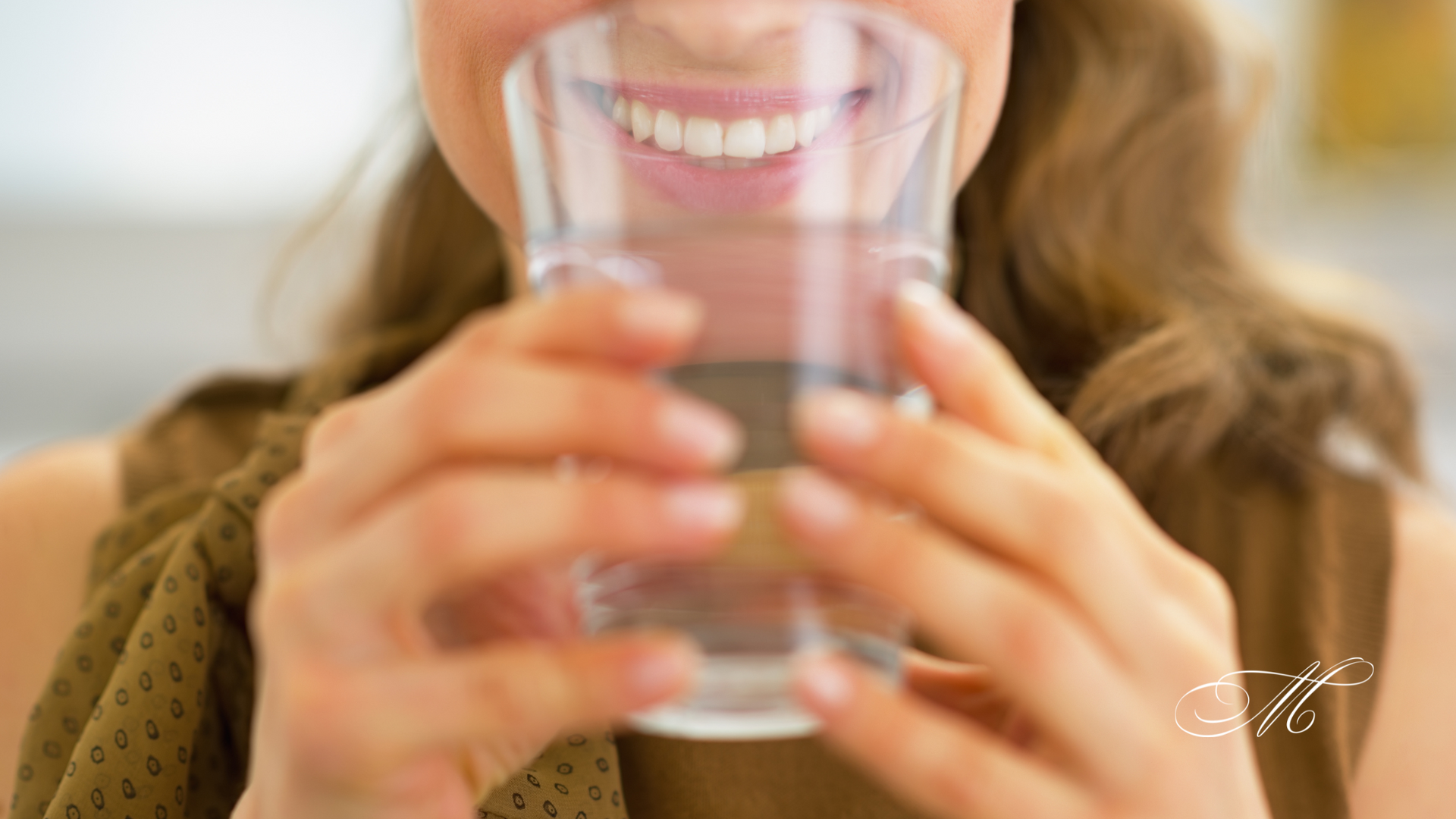 A woman is drinking a glass of water with her mouth open.