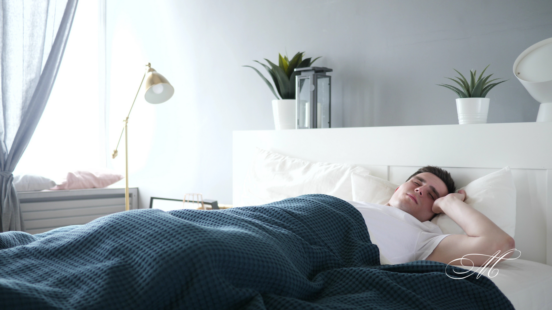 A man is sleeping in a bed with a blue blanket.