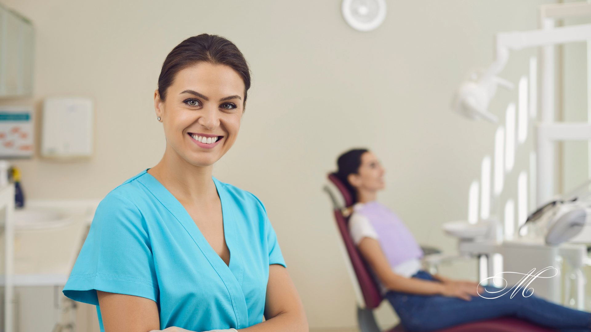 A female dentist is smiling in front of a patient in a dental chair.
