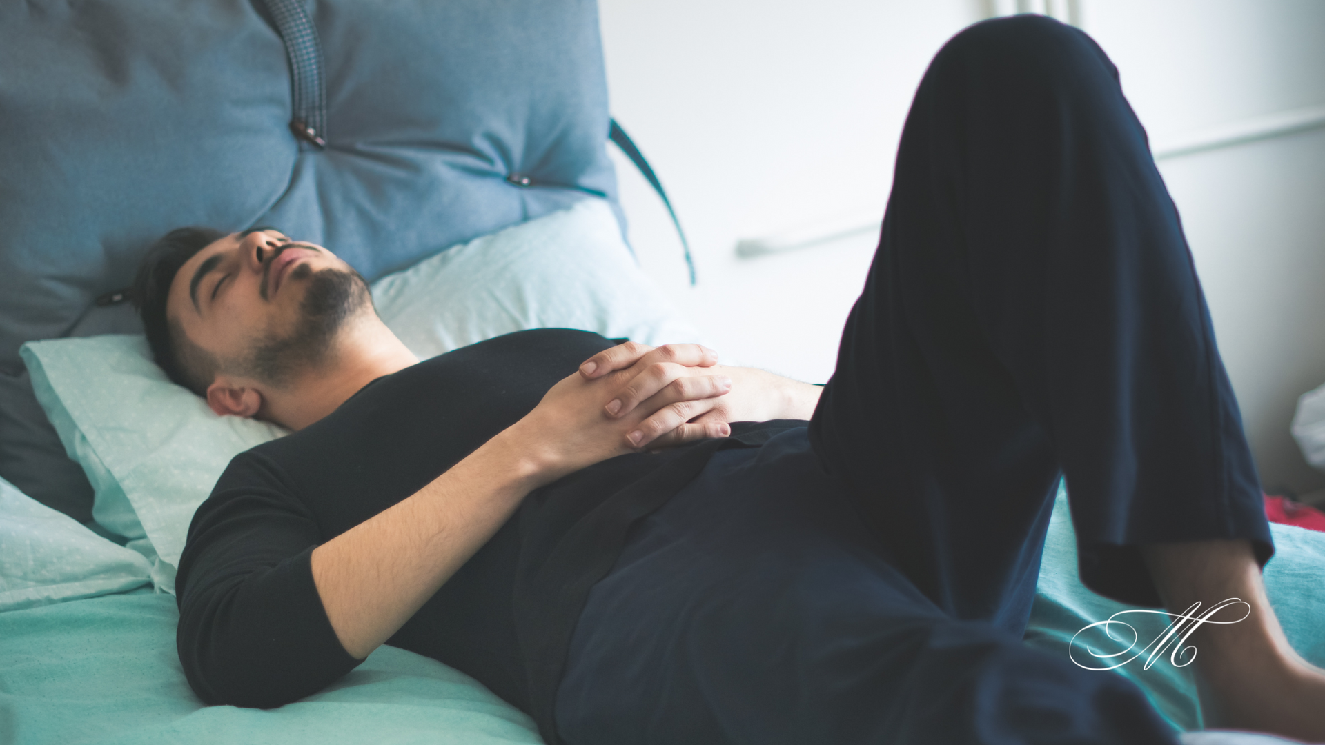 A man is laying on a bed with his legs crossed.