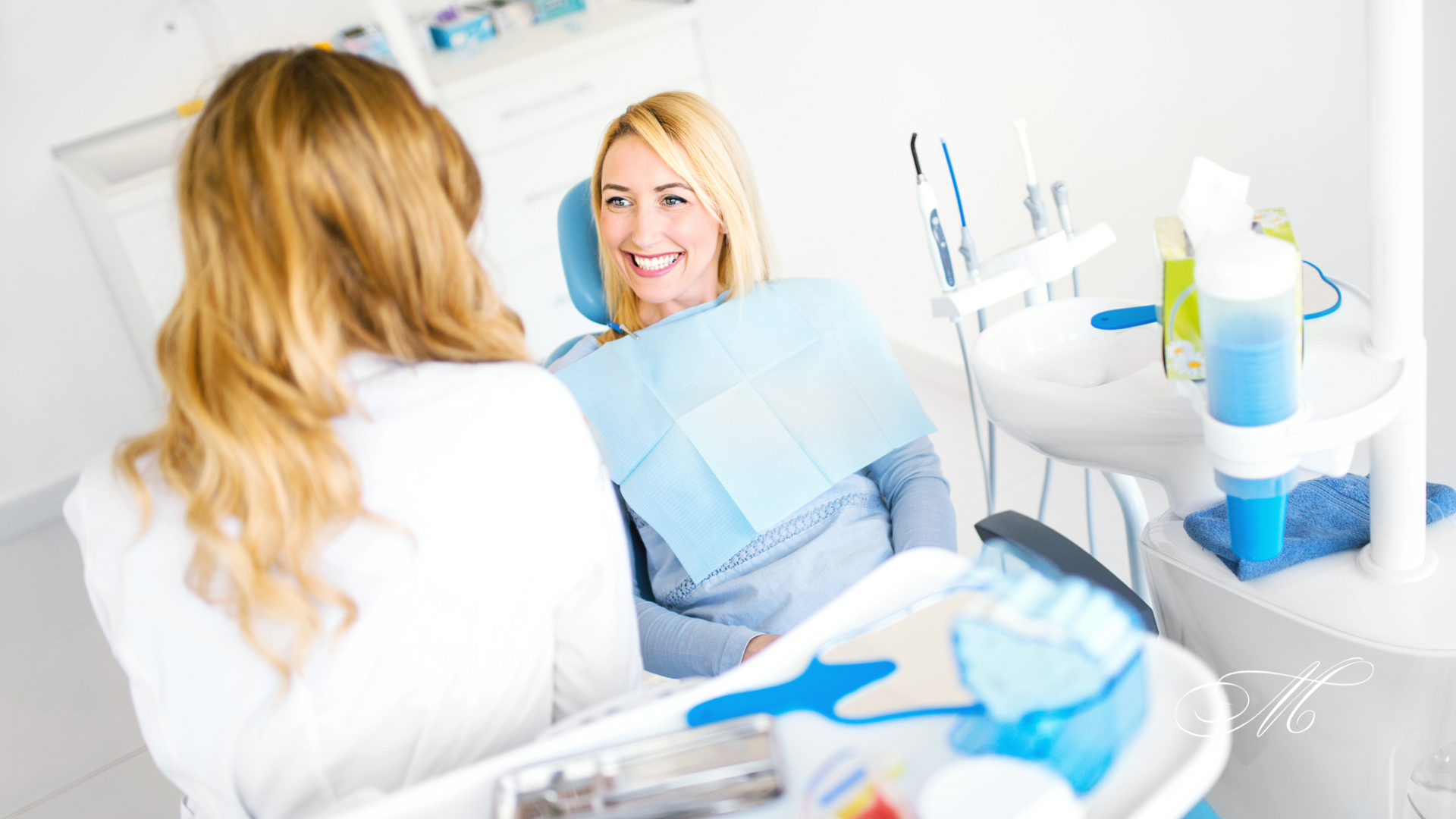 A woman is sitting in a dental chair talking to a dentist.