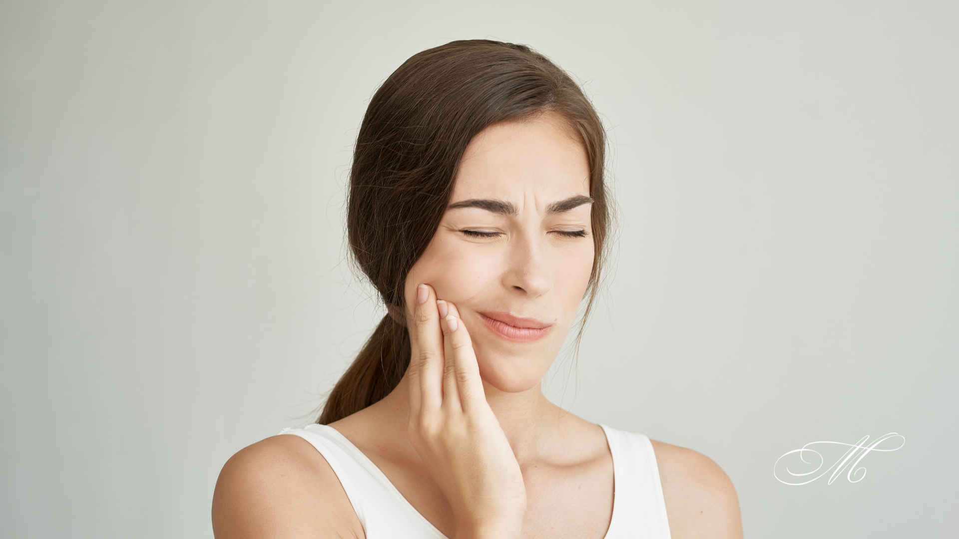A woman is holding her face in pain because of a toothache.