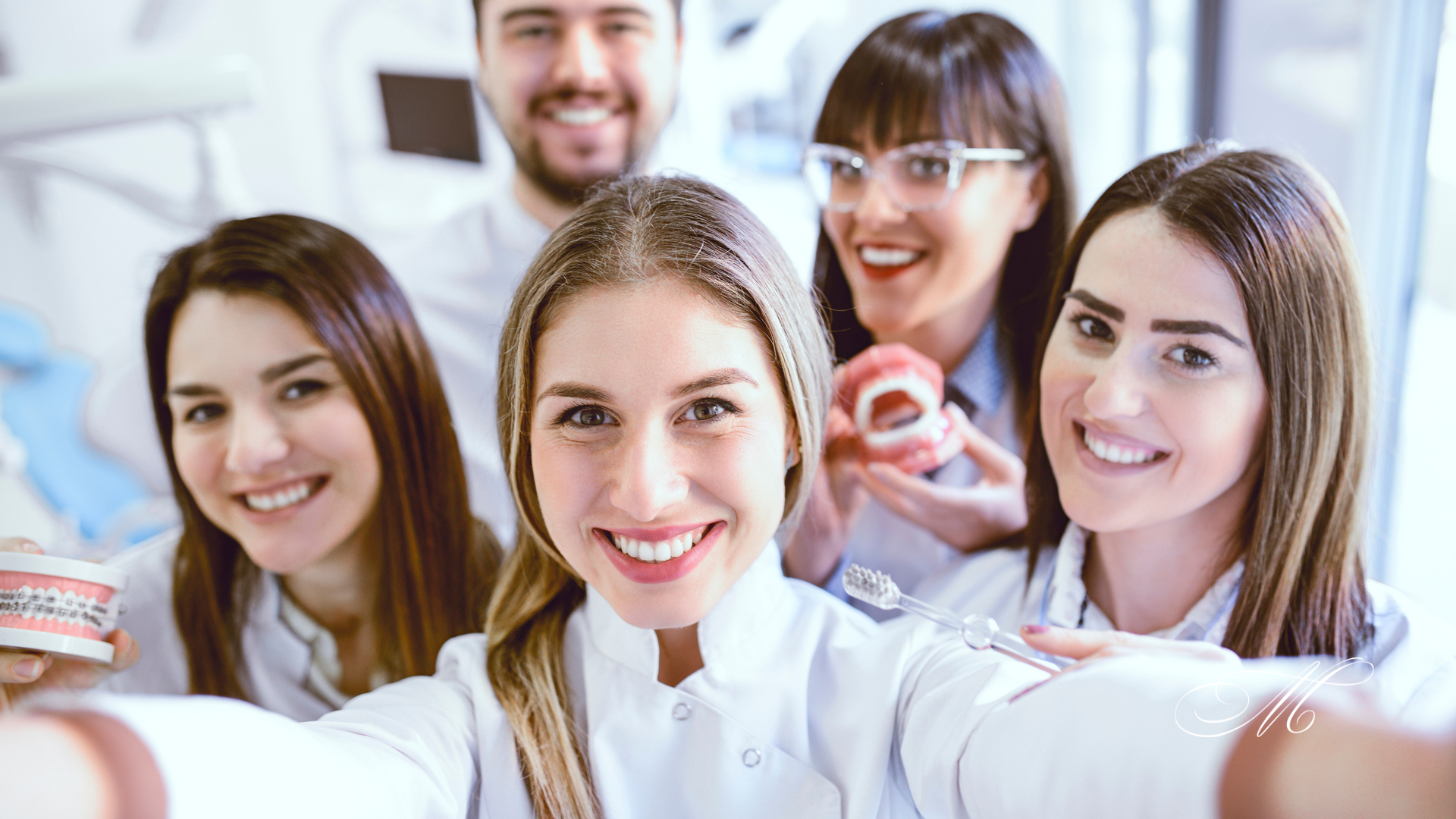 A group of dentists are taking a selfie in a dental office.