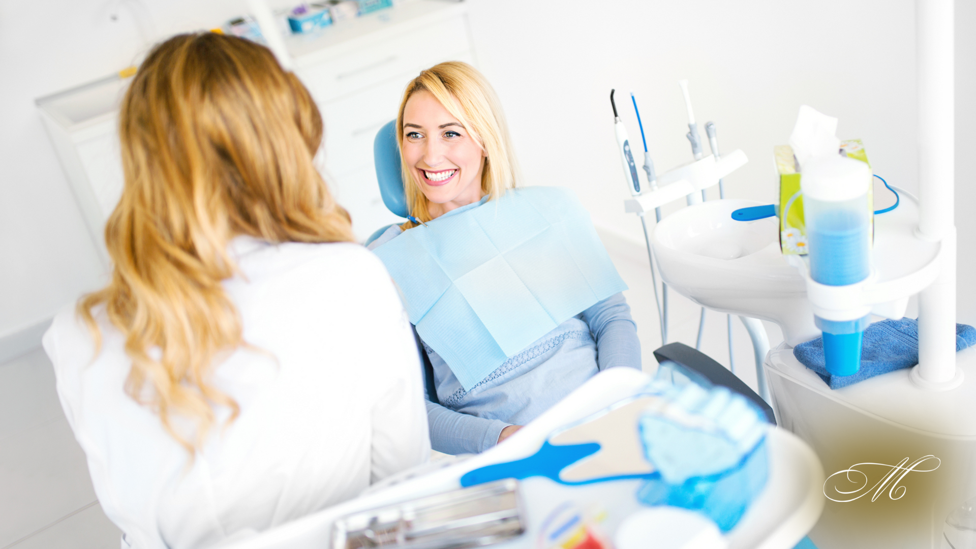 A woman is sitting in a dental chair talking to a dentist.