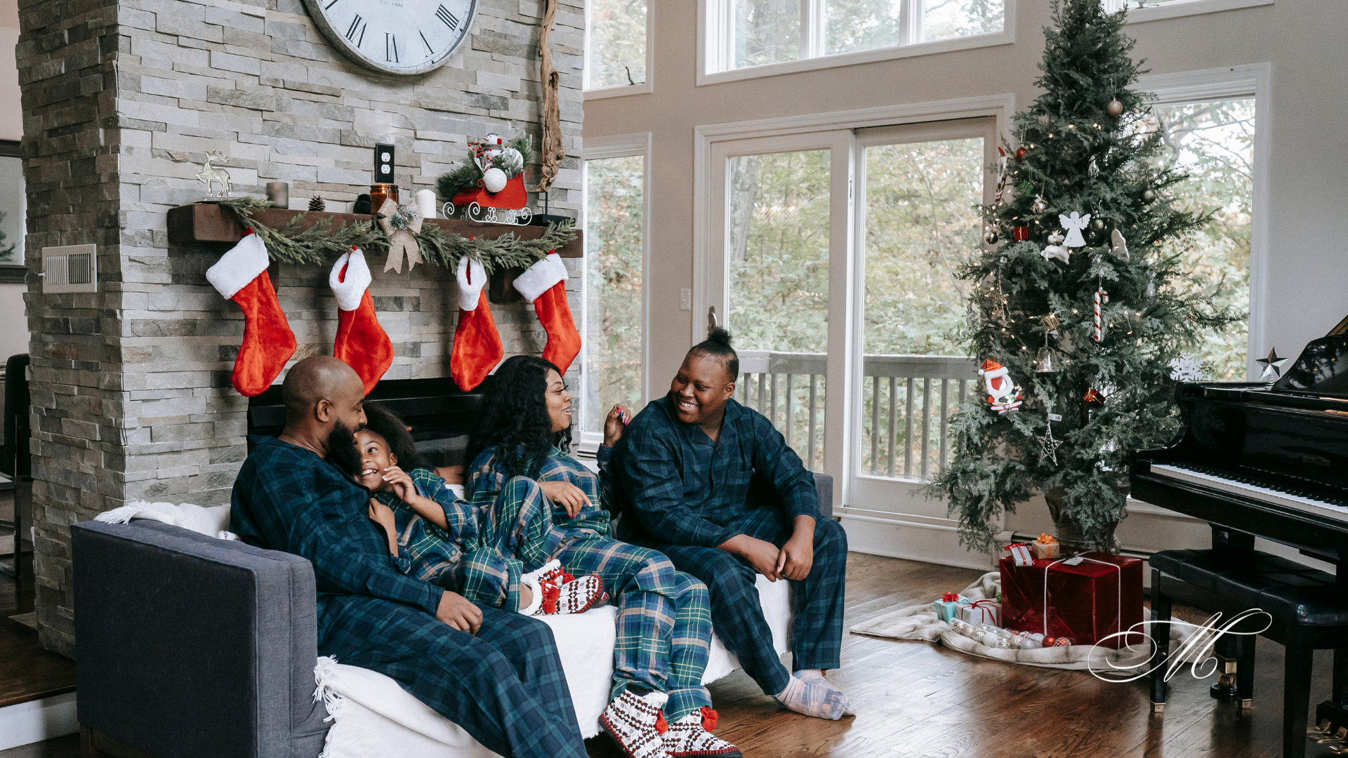 A family is sitting on a couch in front of a christmas tree in a living room.