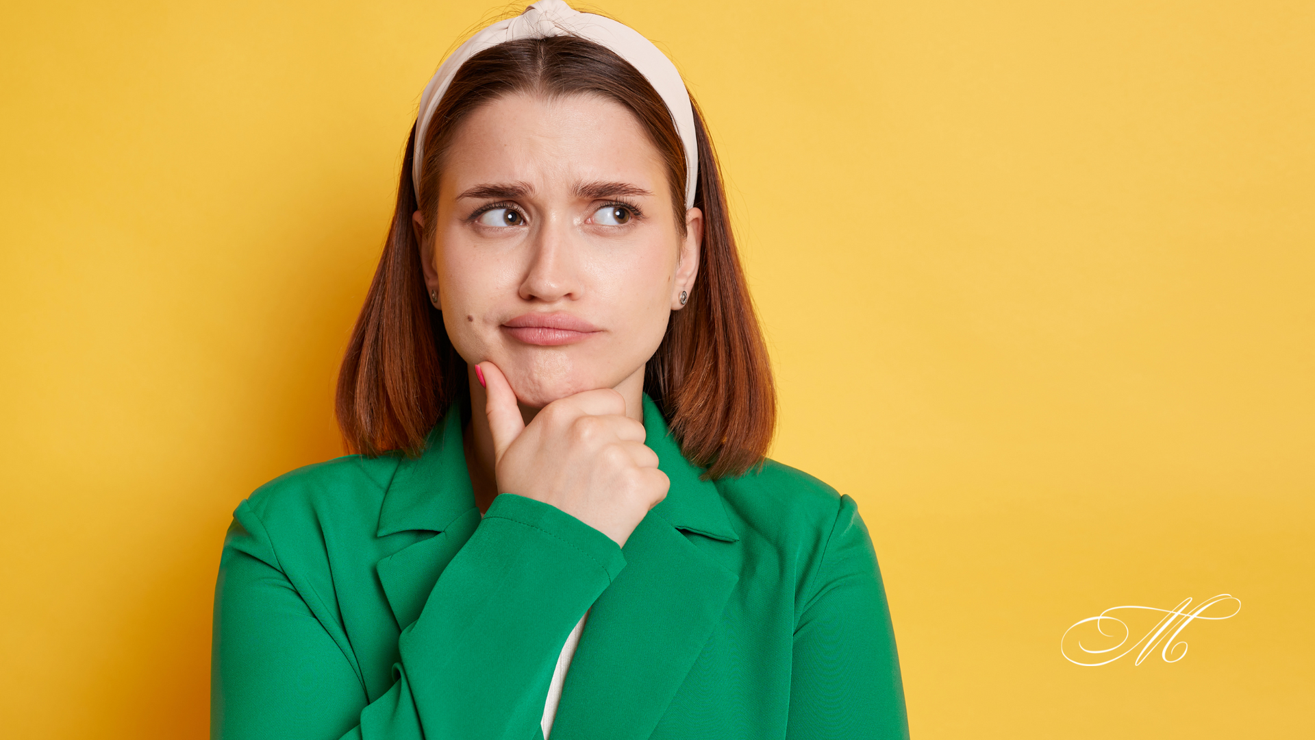 A woman in a green jacket and headband is thinking.