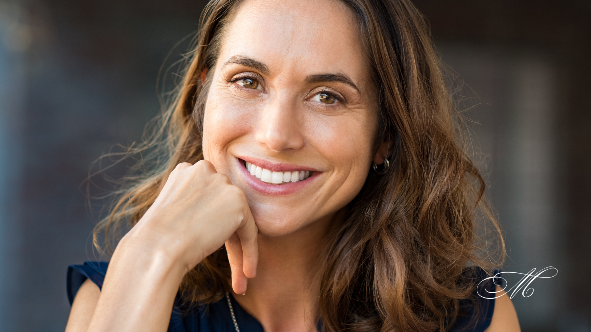A woman is smiling with her hand on her chin.