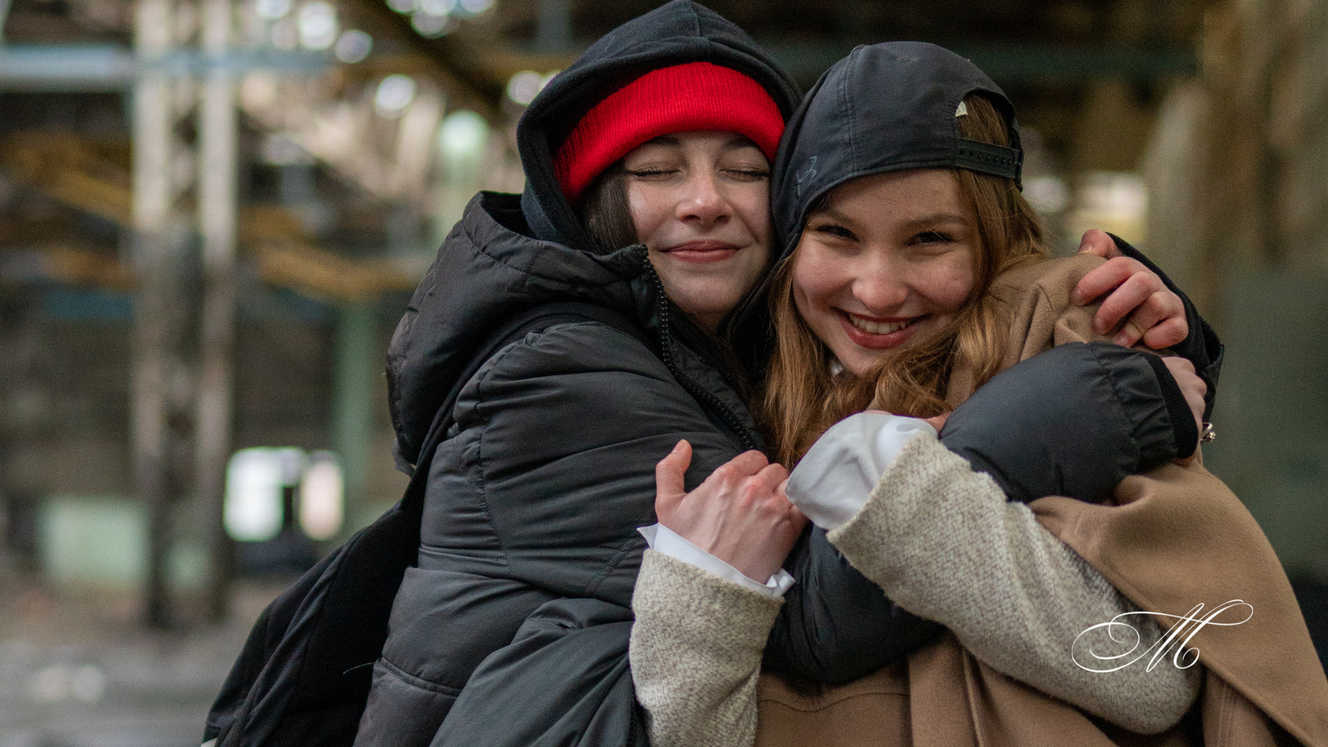 Two girls are hugging each other and smiling for the camera.