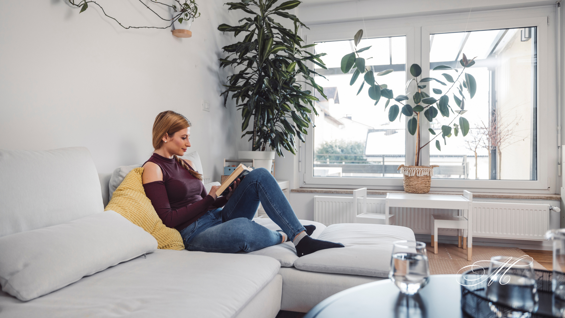 A woman is sitting on a couch reading a book.