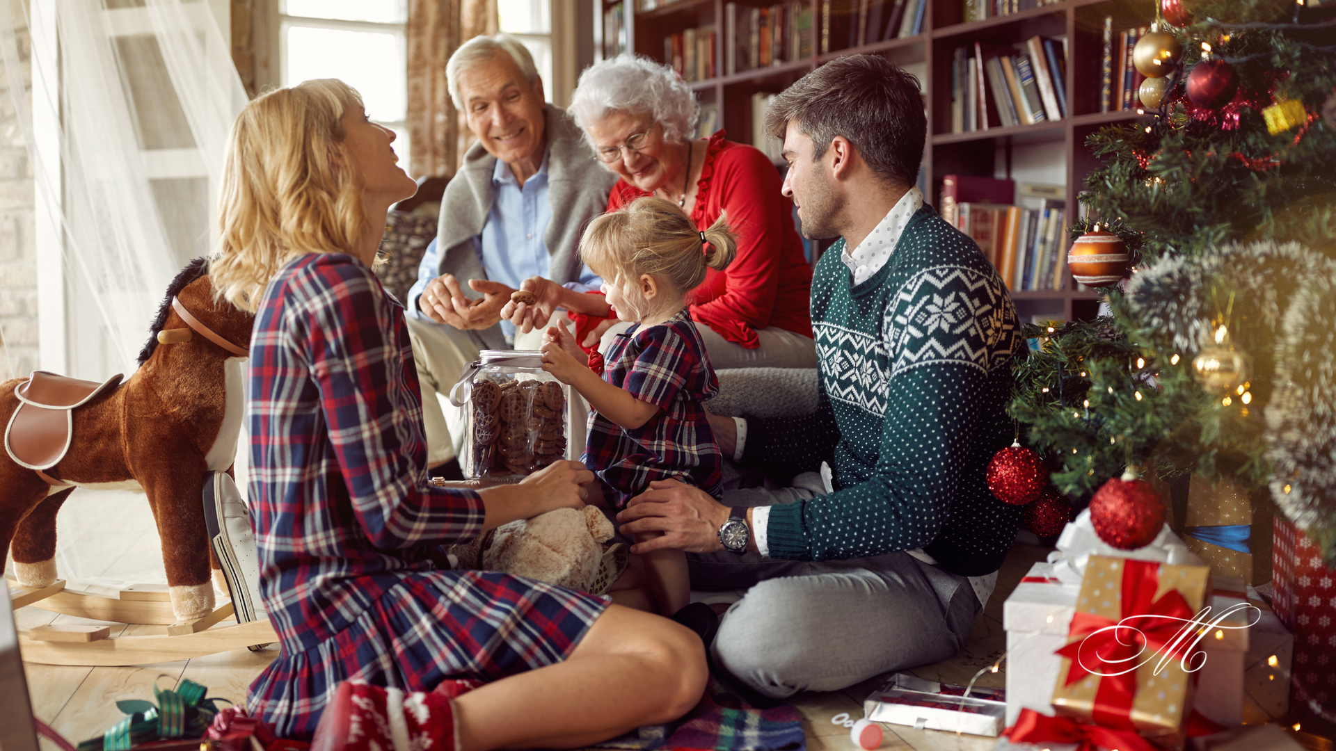 A family is sitting on the floor in front of a christmas tree.