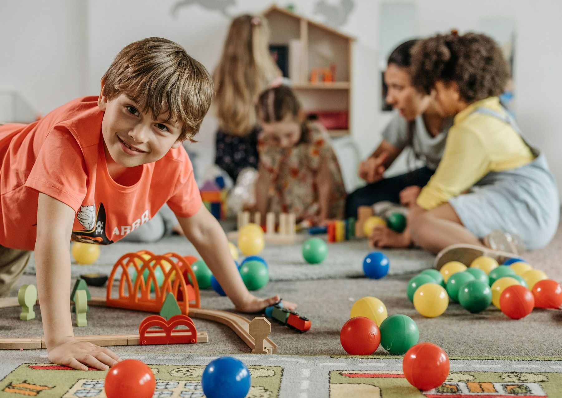 A group of children are playing with toys on the floor.